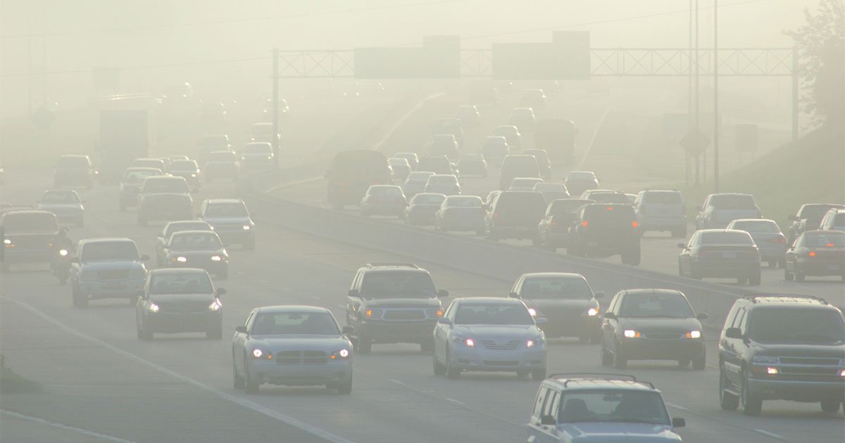 many cars in traffic on a highway with thick hazy smog in the air