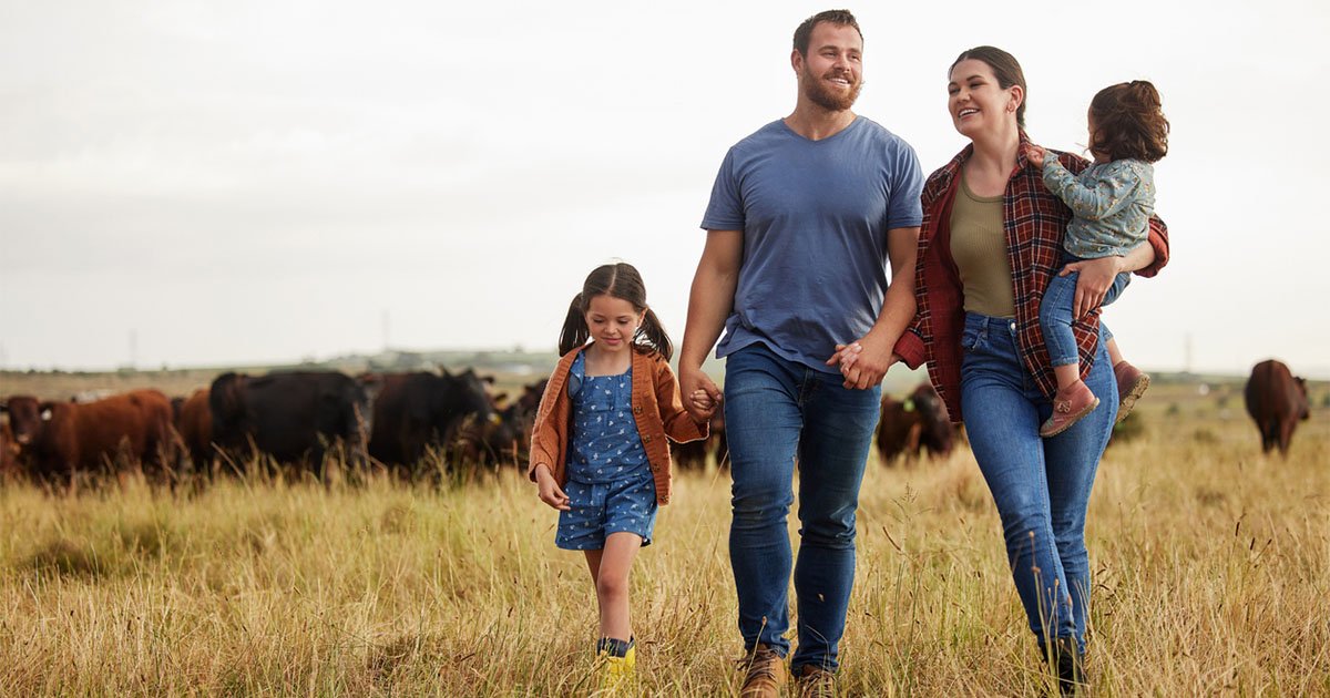 Family of a man a woman and two small children walking in a rural farm field